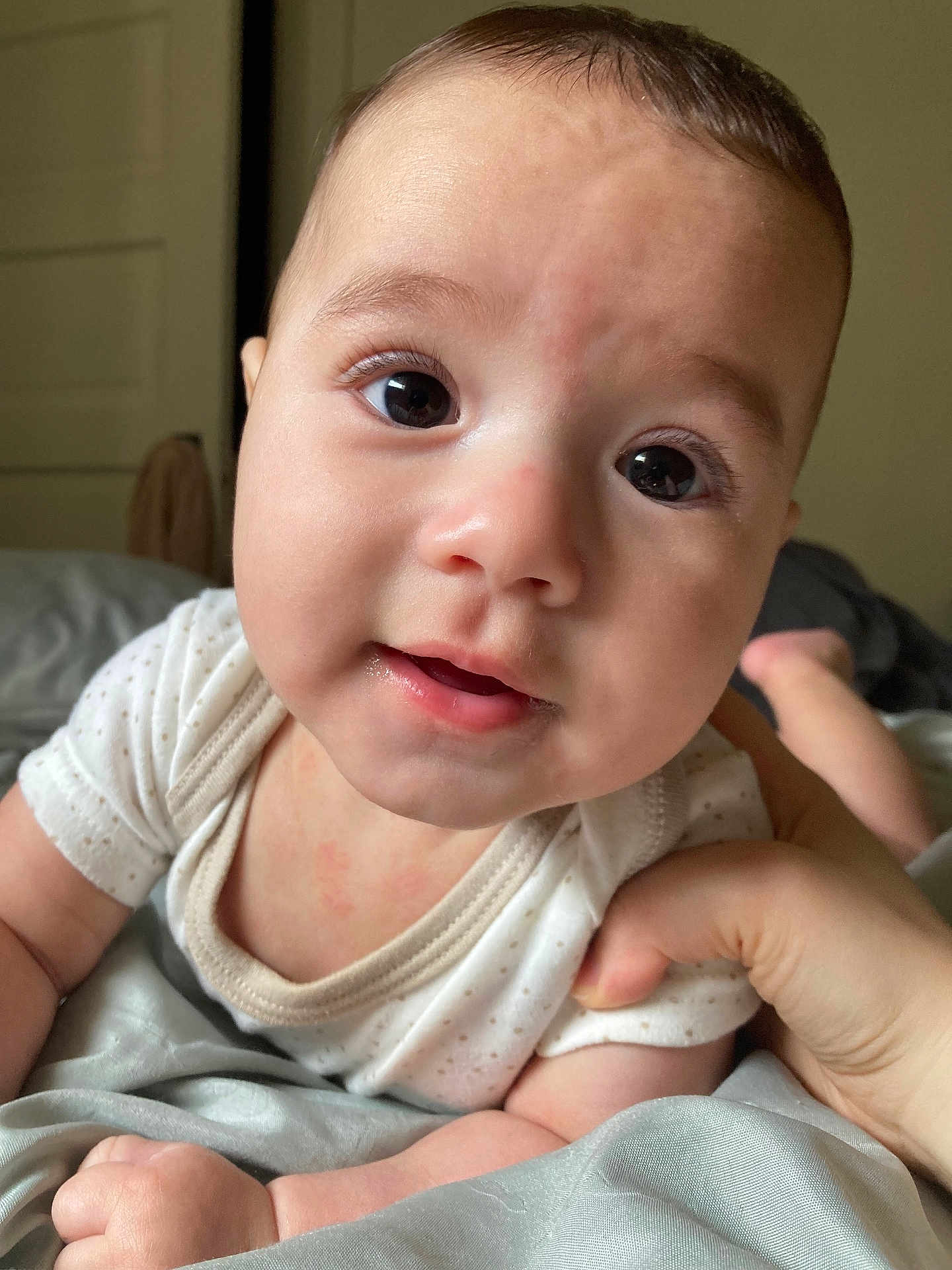 Jamiel is registered to the contest to win money with this photo: baby, infant, face, hand, eyes, mouth, skin, clothing, bed, blanket, person, cute, indoors, sleepwear, newborn, portrait, soft, expression, child, toddler
