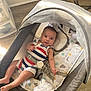 baby, infant, bassinet, striped_clothing, child, indoor, floor, fabric, pattern, mattress, toy, comfort, relaxing, cute, person, face, sleeping_area, baby_gear, foot, hand