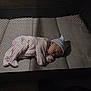 Loretta is registered to the contest to win money with this photo: baby, sleeping, playpen, mesh, infant, hat, blanket, soft_lighting, footwear, carpet, indoor, cozy, child, cute, resting, pajamas, peaceful, person, nursery, baby_sleep