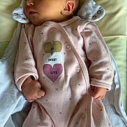 Jade participe au concours pour gagner de l'argent avec cette photo : baby, newborn, sleeping, infant, onesie, pink_clothing, heart_pattern, pillow, blanket, soft_fabric, cute, peaceful, fist, face, skin, head, ear, indoor, rest, child