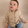 baby, infant, child, portrait, striped_shirt, button_up_shirt, jeans, sitting, studio_background, neutral_background, curious_expression, big_eyes, long_eyelashes, soft_lighting, casual_clothing, hand, legs, cute, neutral_tones, one_person