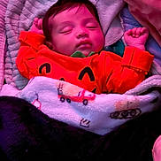Liam joined the competition — help win amazing prizes! baby, infant, sleeping, portrait, face, red_outfit, blanket, wrapped, indoors, cozy, peaceful, closed_eyes, newborn, lying_down, bedding, colorful, pink_lighting, purple_lighting, cute, photography
