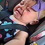 Enola is registered to the contest to win money with this photo: baby, car_seat, child, crying, purple_bow, headband, floral_outfit, infant, seatbelt, close_up, expression, face, skin, arm, indoors, child_protection, travel, safety, colorful_toys, emotion
