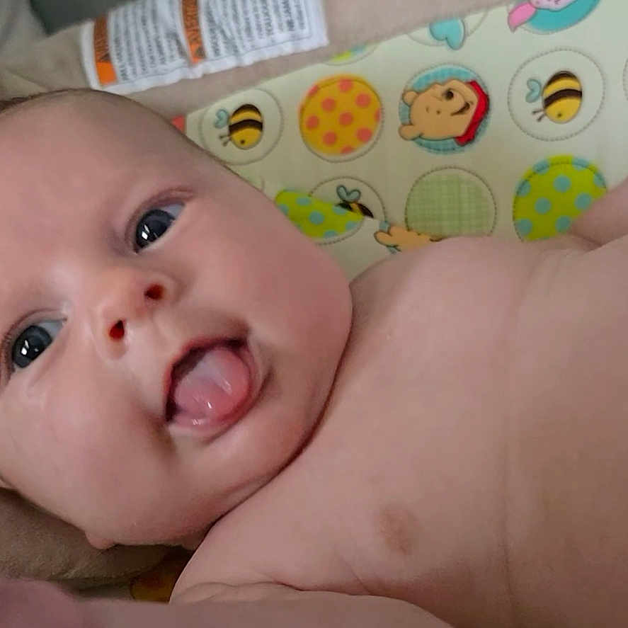Clover Baylin is registered to the contest to win money with this photo: adorable, baby, cheeks, child, closeup, cute, diaper, expression, eyes, face, indoors, infant, lying_down, padded_surface, pattern, person, playful, skin, soft, tongue_out