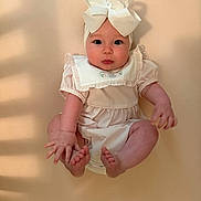 Felicity joined the competition — help win amazing prizes! baby, infant, child, headband, bow, cute, sitting, soft_lighting, beige_background, portrait, chubby_cheeks, curious_expression, clothing, ruffles, skin, hands, feet, closeup, indoor, young