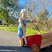 Lowen a rejoint le concours — aidez-le/la à gagner de superbes lots ! toddler, child, pacifier, cap, toy_cart, wooden_toy, outdoor, sunny, greenery, sky, pathway, play, exploration, casual_clothing, jeans, long_sleeve_shirt, shoes, nature, daylight, portrait