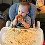 toddler, child, high_chair, messy, food, sauce, face, hands, blue_eyes, gray_shirt, couch, purse, living_room, baby_food, tray, hair, indoor, seat, expression, young_child
