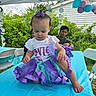 Everleigh joined the competition — help win amazing prizes! toddler, child, party, tutu, purple_bow, table, blue_tablecloth, balloons, outdoor, tent, people, greenery, smiling, celebration, curly_hair, white_shirt, decorations, folding_chairs, person, casual_clothing