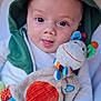 baby, child, hoodie, green, plush_toy, colorful, cute, face, smile, hand, white_clothing, soft_toy, indoor, portrait, young_child, infant, closeup, playful, happy, person