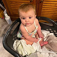 Tatum joined the competition — help win amazing prizes! baby, child, laundry_basket, towels, clothes, floor, wooden_cabinet, indoor, person, sitting, curious, cute, infant, skin, hair, eyes, hands, feet, fabric, home