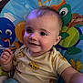 baby, child, smiling, face, infant, cute, indoors, seat, colorful, cartoon, playful, clothing, sun_pattern, happy, portrait, young, person, baby_toy, background, closeup