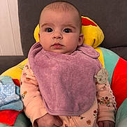 Victoria a rejoint le concours — aidez-le/la à gagner de superbes lots ! baby, infant, child, purple_bib, floral_onesie, plush_seat, soft_toy, clip, indoor, couch, cute, expression, face, hand, sitting, clothing, comfort, young_child, portrait, person