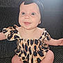 baby, infant, child, smiling, headband, bow, leopard_print, dress, sitting, couch, indoor, cute, happy, blue_eyes, drool, skin, portrait, person, apparel, fabric