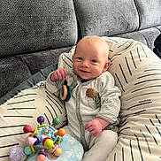 Aaron a rejoint le concours — aidez-le/la à gagner de superbes lots ! baby, smiling, toy, cushion, couch, infant, clothing, happy, indoor, person, face, hand, plush_toy, pattern, fabric, seated, cute, child, relaxing, home