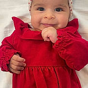 Eleni joined the competition — help win amazing prizes! baby, child, infant, portrait, smiling, happy, red_dress, headband, bow, hearts, lying_down, bed, blanket, indoor, face, eyes, hands, fashion, cute, photography