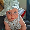 Sophia is registered to the contest to win money with this photo: baby, child, plaid_hat, blue_eyes, curious, close_up, indoor, person, cute, infant, hat, sitting, skin, clothing, portrait, young_child, face, human, lap, home