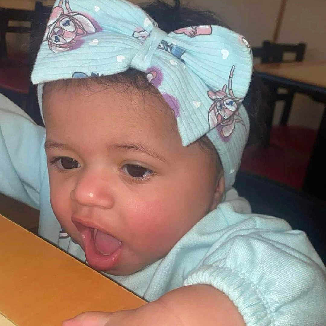 Khalessi joined the competition — help win amazing prizes! accessories, baby, baseballcap, bodypart, cap, clothing, cutlery, face, finger, furniture, hand, hat, head, indoors, mouth, person, photography, portrait, table, teeth