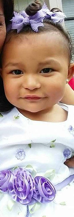 Isabel is registered to the contest to win money with this photo: cheek, child, day, eye, eyebrow, face, forehead, hair_accessory, hairstyle, head, human_hair_color, infant, lavender, lilac, nose, person, product, purple, skin, smile