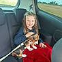 child, girl, dog, puppy, beagle, car_interior, backseat, seat, seatbelt, blanket, pet, animal, leash, smile, braids, window, countryside, travel, happy, young
