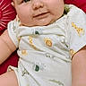 baby, infant, child, onesie, animal_print, giraffe, lion, zebra, cushion, red_background, smile, cute, chubby_cheeks, relaxed, indoors, portrait, skin, hand, face, happy