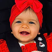 Ania a rejoint le concours — aidez-le/la à gagner de superbes lots ! baby, child, smiling, red_headband, red_bow, red_clothing, car_seat, black_straps, face, happy, teeth, infant, cute, closeup, portrait, person, baby_girl, headwear, accessory, safety