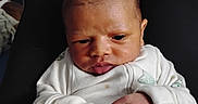 Anthony is registered to the contest to win money with this photo: baby, casual, child, clothing, cozy, cute, expression, face, hands, human, indoor, infant, lap, newborn, onesie, person, portrait, sitting, skin, young