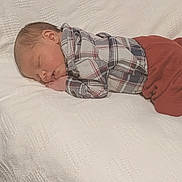 Anthony is registered to the contest to win money with this photo: baby, newborn, sleeping, plaid_shirt, red_pants, blanket, soft_texture, peaceful, resting, infant, cute, face, clothing, lying_down, indoors, portrait, child, young, cozy, comfort