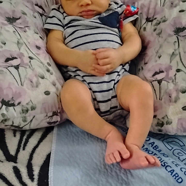 Anthony joined the competition — help win amazing prizes! baby, newborn, sleeping, striped_onesie, pillow, floral_pattern, blanket, carpet, feet, hands, infant, child, cute, resting, indoors, soft, comfort, portrait, person, cozy
