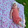 Scarlett joined the competition — help win amazing prizes! baby, baby_photography, bow, child, coral_outfit, floral_blanket, flower_pattern, garden, grass, headband, infant, knit_clothing, lying_down, natural_light, outdoor, pink, portrait, raised_fist, serious_expression, shoes