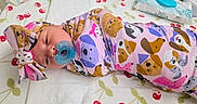 Scarlett joined the competition — help win amazing prizes! animal_print, baby, baby_supplies, bedding, changing_mat, cherry_pattern, child, colorful_clothing, crib, diapers, headband, indoor, infant, lying_down, nursery, pacifier, pink_outfit, portrait, swaddled, wide_eyed