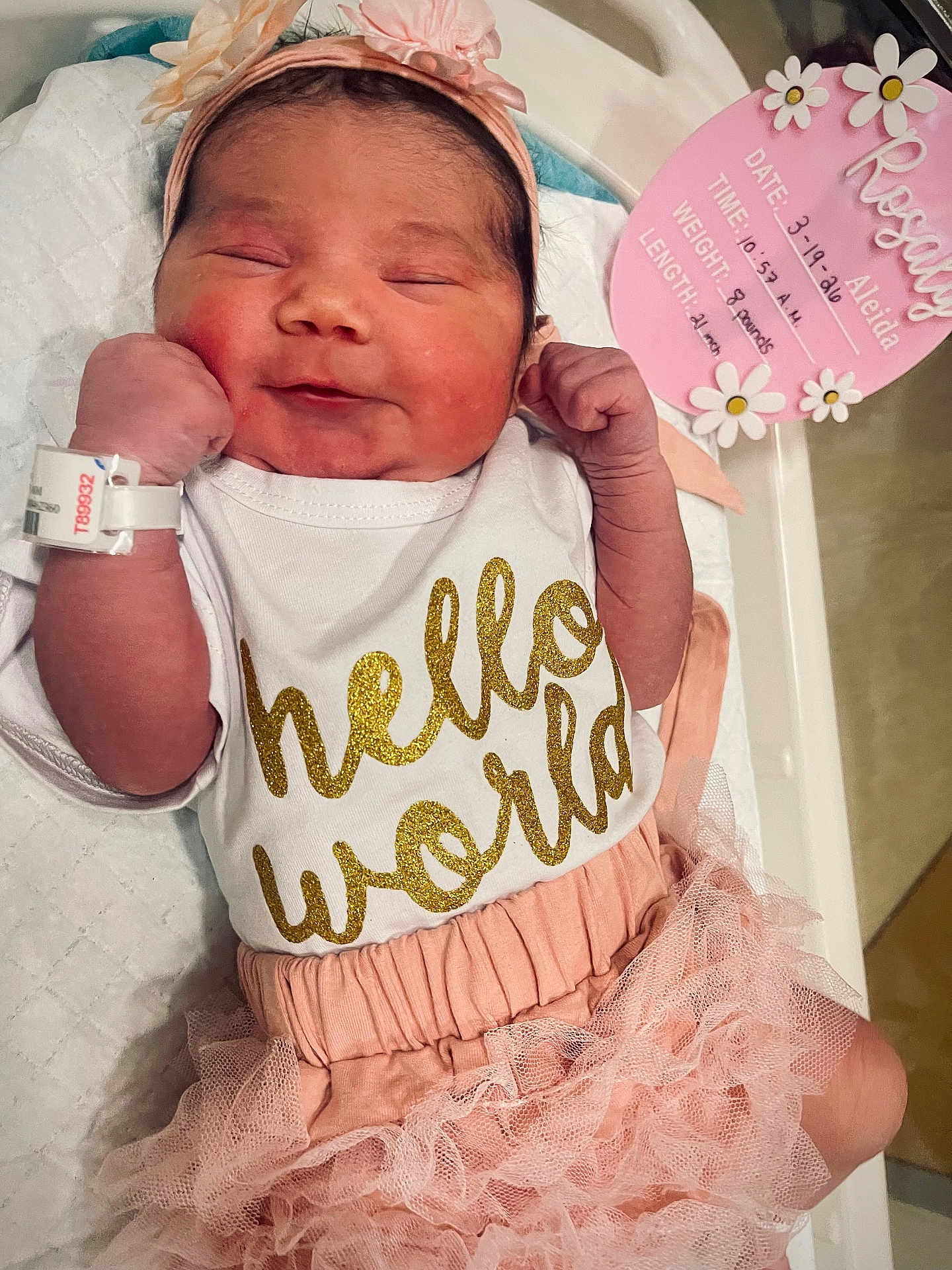 Rosaly Aleida Corzo is registered to the contest to win money with this photo: newborn, baby, infant, smiling, headband, hospital, hospital_bed, clothing, pink, ruffle_skirt, bracelet, face, person, cute, lying_down, birth_announcement, text, hand, skin, sleepy