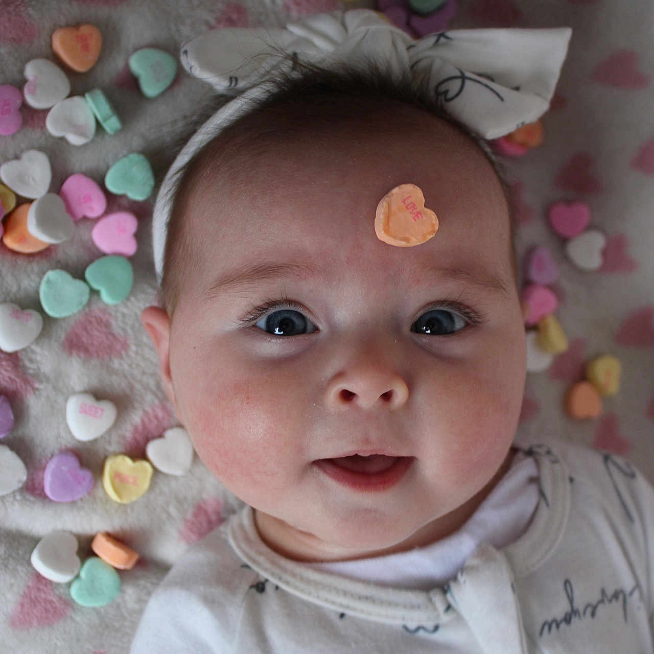 Scarlett is registered to the contest to win money with this photo: applique, baby, bodypart, bonnet, clothing, confetti, face, finger, hand, hat, head, knitwear, newborn, paper, pattern, person, photography, portrait, sweater, t_shirt