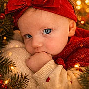 Alma participe au concours pour gagner de l'argent avec cette photo : baby, child, blue_eyes, red_headband, bow, hand_in_mouth, holiday_lights, pine_branches, festive, cozy, warm_colors, sweater, heart_pattern, close_up, portrait, cute, infant, christmas_theme, soft_texture, snuggled
