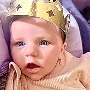 Alma participe au concours pour gagner de l'argent avec cette photo : baby, blanket, blue_eyes, child, close_up, cozy, crown, curious, cute, expression, face, golden_crown, headwear, indoor, infant, looking, pink_sweater, portrait, soft_texture, young_child