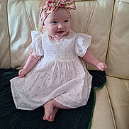Evie is registered to the contest to win money with this photo: baby, baby_girl, blanket, child, comfortable, couch, cute, dress, floral_pattern, happy, headband, indoors, infant, leather, portrait, sitting, small_feet, small_hands, smile, white_dress