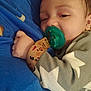 baby, pacifier, sleepy, infant, clothing, hand, face, blue_fabric, grey_outfit, stars, closeup, cute, child, comfort, resting, indoor, young, soft, warm, holding