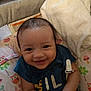 Elijah is registered to the contest to win money with this photo: baby, smiling, infant, blue_shirt, cushion, blanket, owl_pattern, indoor, happy, cute, child, person, seated, comfort, soft_toy, fabric, clothing, face, head, skin