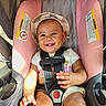 Neziya is registered to the contest to win money with this photo: baby, child, smiling, hat, car_seat, safety_harness, pink, gray, cute, infant, happy, seatbelt, clothing, portrait, young_child, sunlight, indoors, toddler, person, seat
