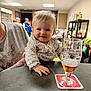 Kira a rejoint le concours — aidez-le/la à gagner de superbes lots ! baby, child, person, table, glass, beer, beverage, indoor, shelf, food, drink, adult, tattoo, clothing, smile, hand, face, room, people, background