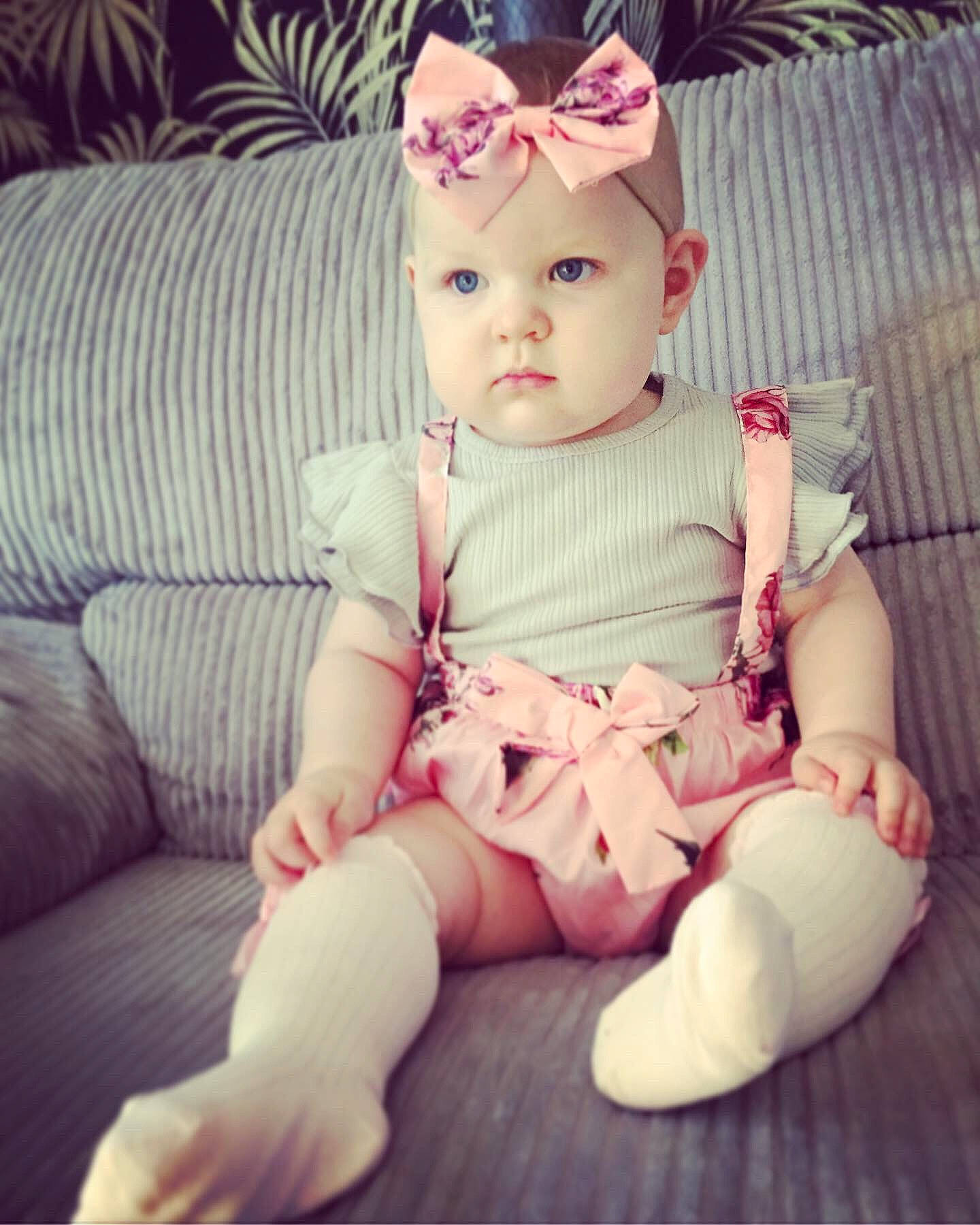 Evie-mae is registered to the contest to win money with this photo: baby, beauty, cheek, child, ear, eye, face, forehead, hair_accessory, head, headgear, joint, leg, lip, person, pink, product, sitting, skin, smile