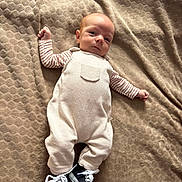 Noah participe au concours pour gagner de l'argent avec cette photo : baby, infant, blanket, clothing, overalls, striped_sleeves, sneakers, footwear, lying_down, texture, fabric, cute, portrait, child, small, young, casual, comfortable, indoors, resting