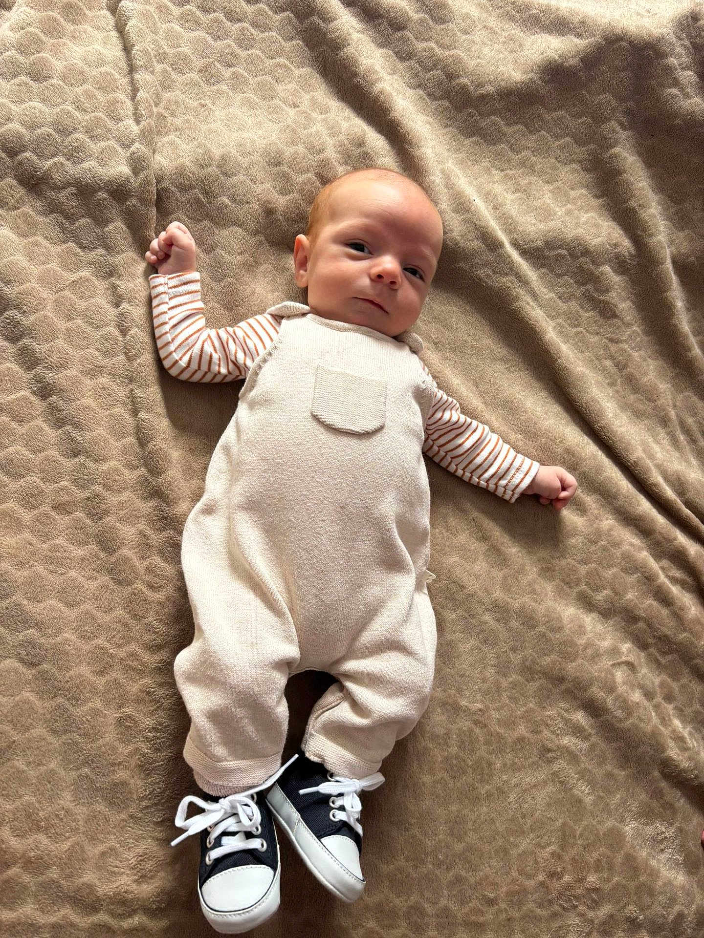 Noah participe au concours pour gagner de l'argent avec cette photo : baby, infant, blanket, clothing, overalls, striped_sleeves, sneakers, footwear, lying_down, texture, fabric, cute, portrait, child, small, young, casual, comfortable, indoors, resting