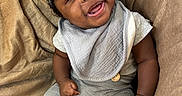 Azaiah joined the competition — help win amazing prizes! baby, smiling, child, infant, hat, gray_clothing, socks, blanket, soft_texture, happy, cute, portrait, indoor, seated, cozy, young_child, person, face, hands, warm