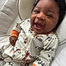 baby, child, infant, smiling, laughing, onesie, animal_print, curly_hair, cushion, soft_fabric, indoor, happy, cute, closeup, portrait, relaxed, cozy, person, seated, comfortable