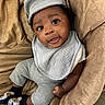 Azaiah is registered to the contest to win money with this photo: baby, infant, child, smiling, face, cap, bib, socks, plush_chair, cozy, clothing, happy, portrait, indoor, cute, seated, looking_up, soft_texture, skin, expression