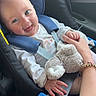baby, car_seat, blue_eyes, plush_toy, hand_holding, car_interior, smiling, child, seatbelt, clothing, person, infant, safety, cute, happy, parent, travel, seat, window, arm