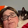 person, cat, glasses, indoor, shoulder, black_and_white_cat, face, red_shirt, relaxed, closeup, pet, domestic_animal, home, feline, casual, portrait, comfort, animal_companion, friendship, resting