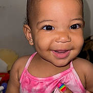 Avierra is registered to the contest to win money with this photo: baby, smiling, child, face, pink_clothing, earrings, hand, rainbow_nails, butterfly, tank_top, skin, portrait, cute, happy, indoor, closeup, person, infant, young_child, joyful