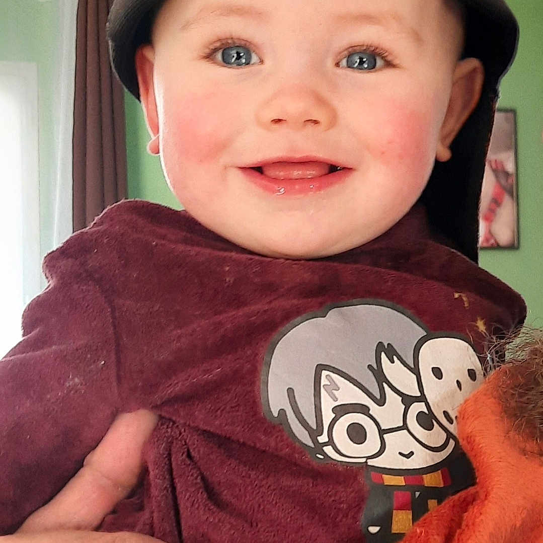 Nathanaël participe au concours pour gagner de l'argent avec cette photo : baby, child, smiling, cap, maroon_shirt, cartoon_character, hand, indoor, portrait, happy, cute, blue_eyes, person, clothing, face, young_child, holding, casual, headwear, expression