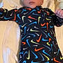 baby, blanket, child, colorful_clothing, comfort, cute, fabric, face, head, indoor, infant, lying_down, newborn, nike_logo, onesie, pattern, person, resting, sleepwear, soft